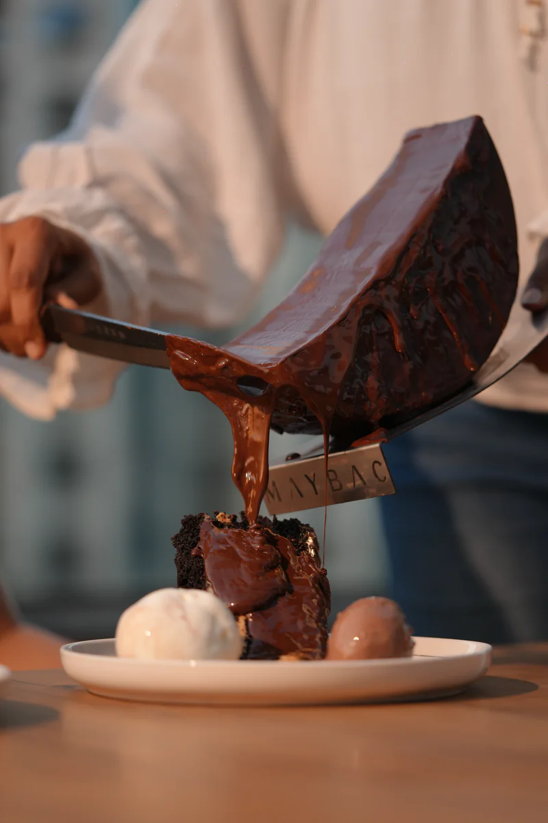 Chocolate raclette scraped from the wheel onto cake and ice cream